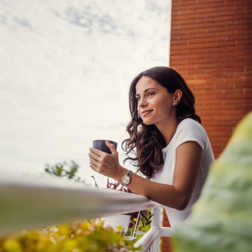 a woman holding a drink and looking out over a balcony
