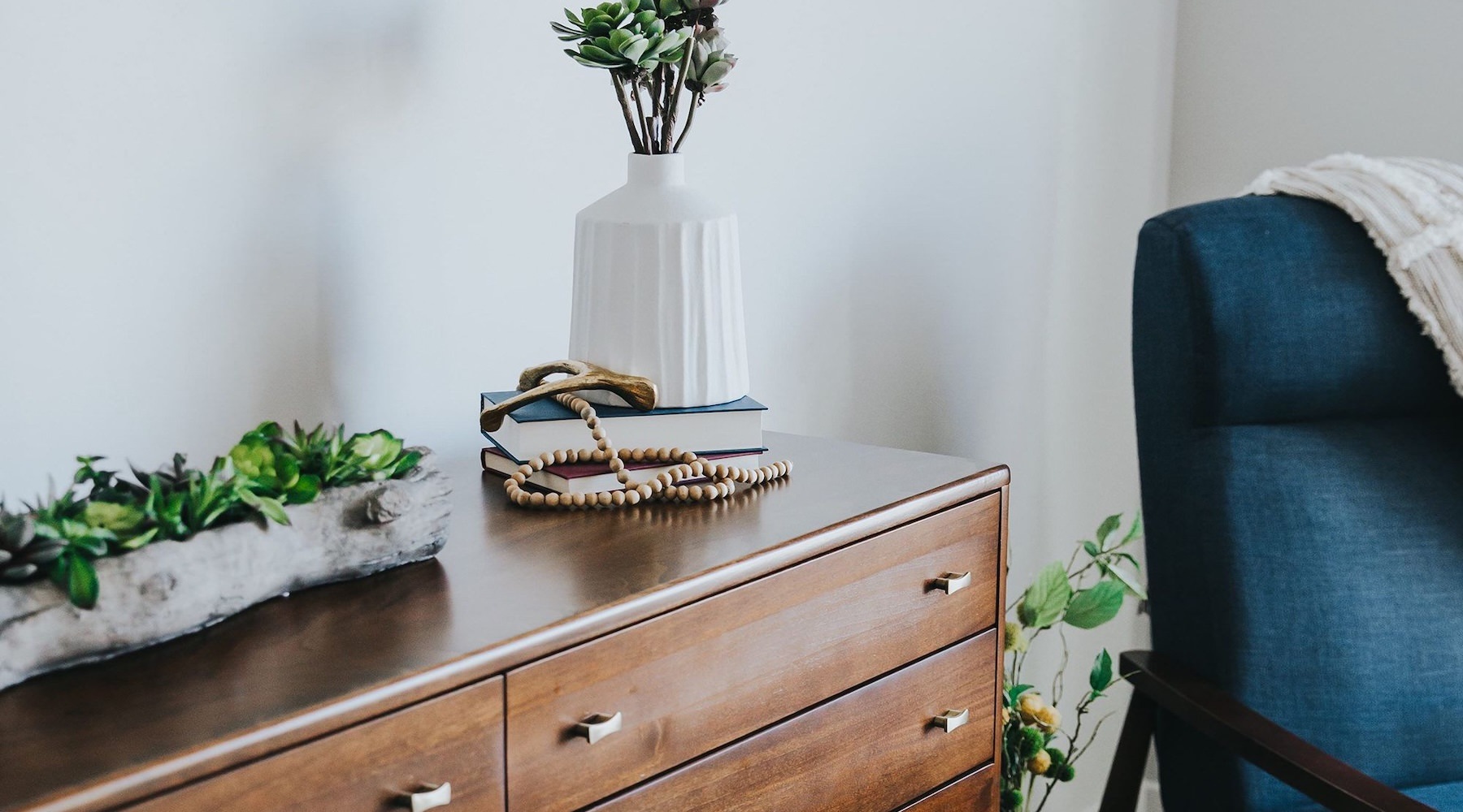 a dresser with a vase of plants on top