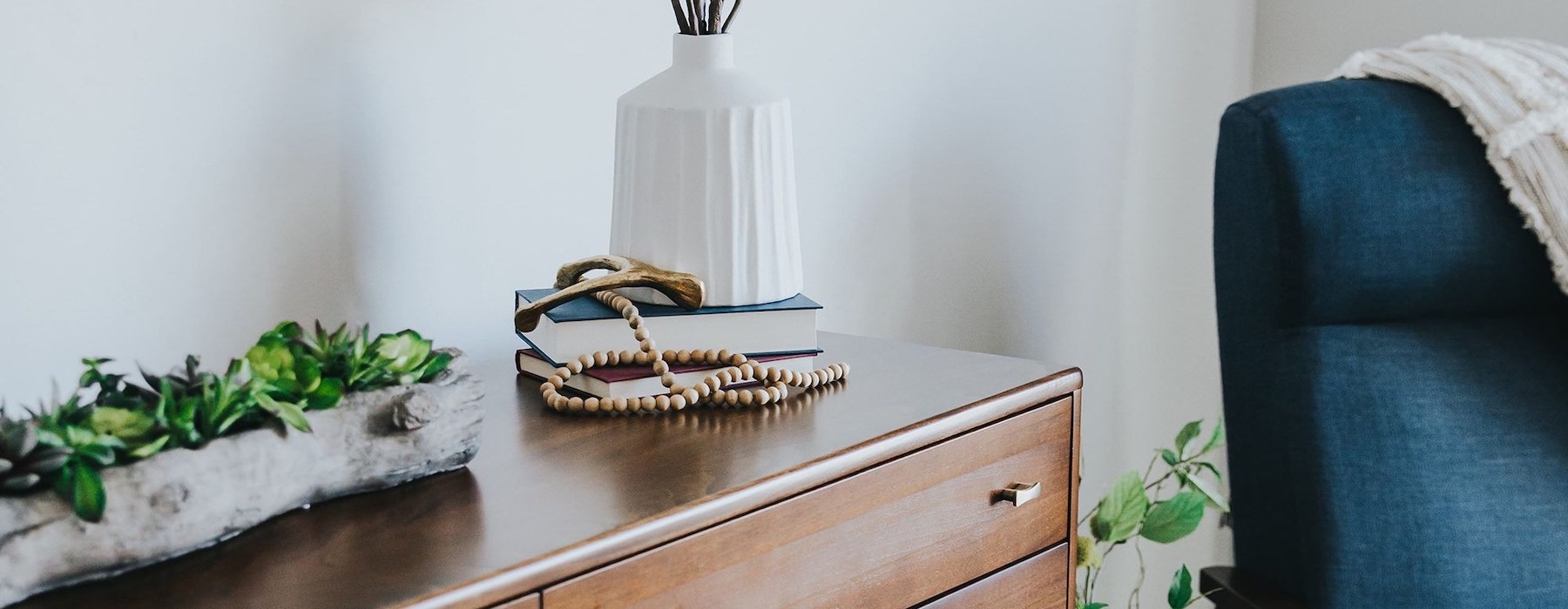 a dresser with a vase of plants on top